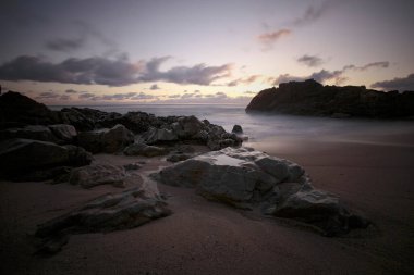 Alacakaranlıkta Rocky plajı. Uzun pozlama. Kuzey Portekiz kıyıları.