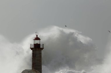 Sprey ile büyük bir dalga sıçraması. Douro Nehri eski deniz feneri. Yumuşak arka ışıklandırma.