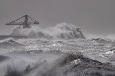 Leixoes harbor north wall with his iconic big crane under heavy storm. clipart