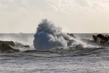 Büyük fırtınalı deniz dalgaları kayaların üzerinde kırılıyor.