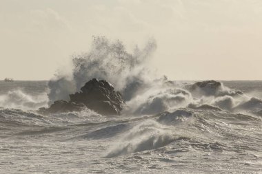 Büyük fırtınalı deniz dalgaları kayaların üzerinde kırılıyor.