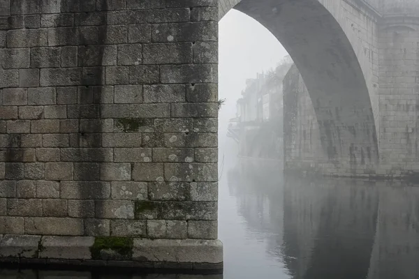 Romantic old river bridge in the middle of fog. Tamega bridge, Amarante, north of Portugal.