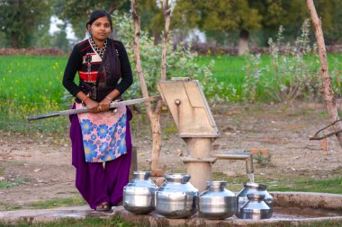 TIKAMGARH, MADHYA PRADESH, INDIA - 23 HAZİRAN 2021: Kimliği belirsiz Hintli kız içme suyu pompası kullanıyor.