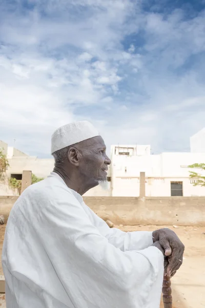 African man sitting in front of his house, eighty years old