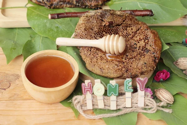 Honung med honeycomb på gröna blad. — Stockfoto