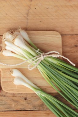Ahşap arka plan üzerinde taze yeşil soğan