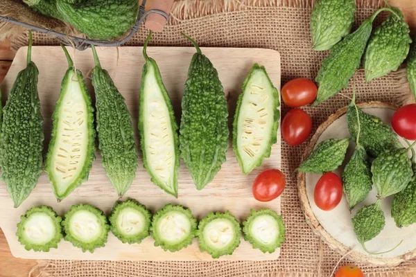 Bitter melon och skivad på trä bakgrund — Stockfoto