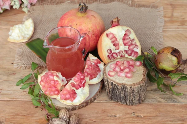 Ripe pomegranates with juice on wood background — Stock Photo, Image