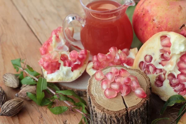 Romãs maduras com suco sobre fundo de madeira — Fotografia de Stock