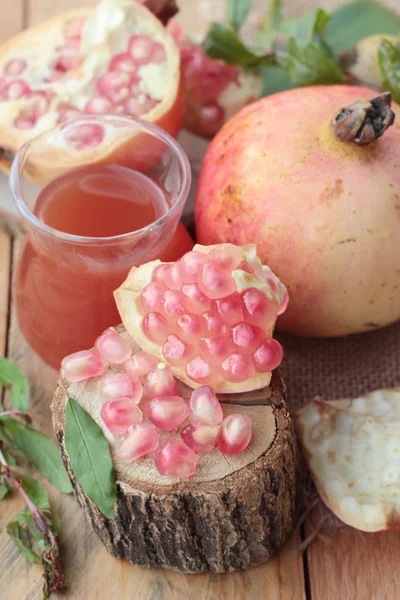 Romãs maduras com suco sobre fundo de madeira — Fotografia de Stock