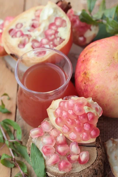 Romãs maduras com suco sobre fundo de madeira — Fotografia de Stock