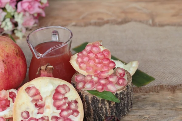 Romãs maduras com suco sobre fundo de madeira — Fotografia de Stock