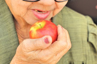 Kırmızı bir elma yiyen kadın kıdemli