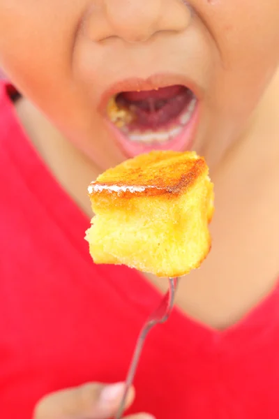 A boy eating toast topped with honey — Stock Photo, Image