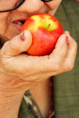 Kırmızı bir elma yiyen kadın kıdemli