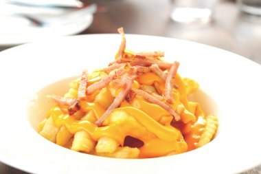 Plaka üzerinde peynir ile kızarmış patates tepesinde.