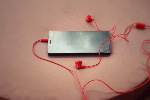 Смартфон с красным наушником — стоковое фото