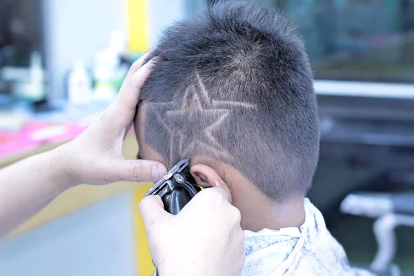 El corte de pelo del niño con el cortador y la navaja de afeitar en la peluquería — Foto de Stock