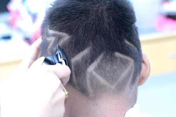 O corte de cabelo do menino com cortador e navalha na barbearia — Fotografia de Stock