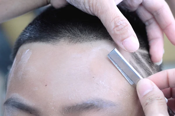 O corte de cabelo do menino com cortador e navalha na barbearia — Fotografia de Stock