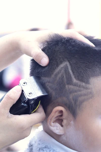 O corte de cabelo do menino com cortador e navalha na barbearia — Fotografia de Stock