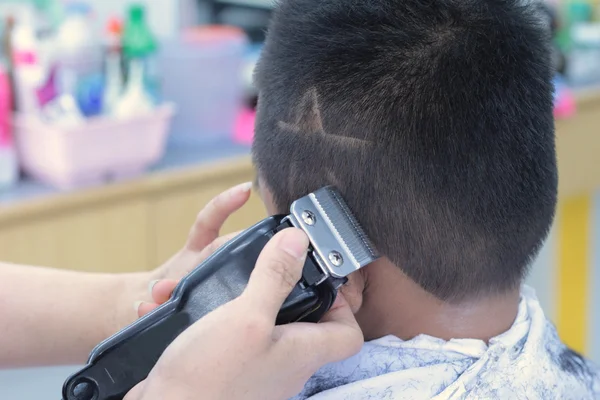 El corte de pelo del niño con el cortador y la navaja de afeitar en la peluquería — Foto de Stock