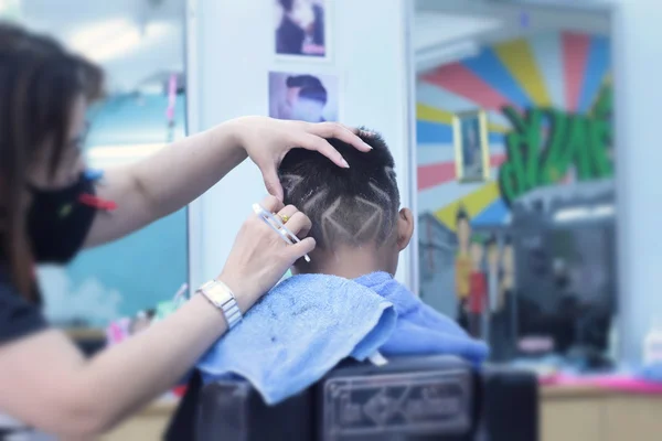 Haarschnitt des Jungen mit Haarschneider und Rasiermesser im Friseurladen — Stockfoto