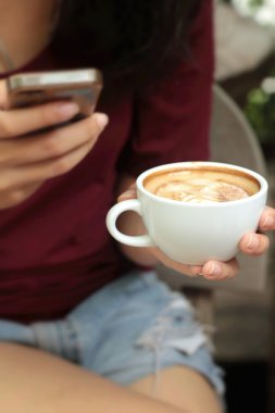 Kahve Kupası ve akıllı telefonlar içme kadın