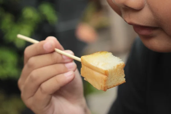 The boy eating toast topped with almonds and honey. — Stock Photo, Image