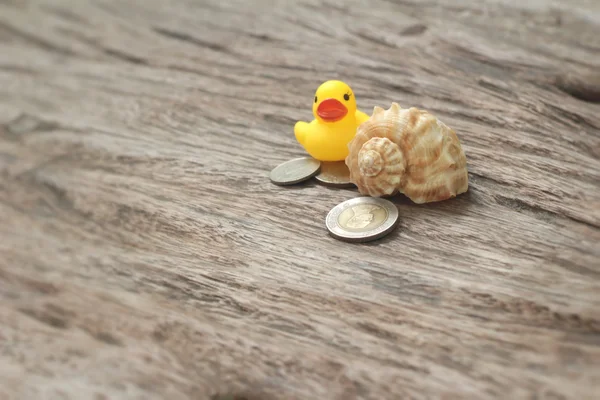 Yellow rubber duck and banknotes ,coins on wood background — Stock Photo, Image