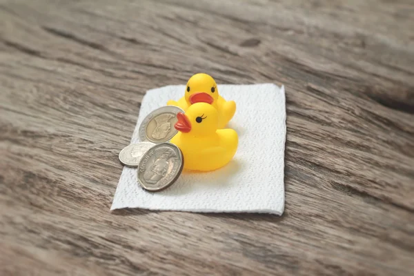 Yellow rubber duck and banknotes ,coins on wood background — Stock Photo, Image