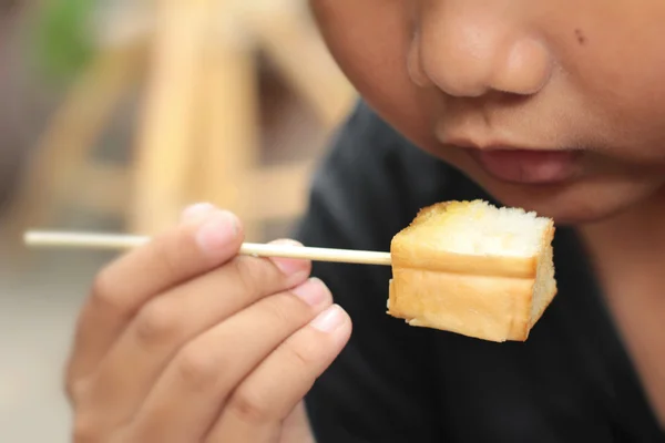 The boy eating toast topped with almonds and honey. — Stock Photo, Image