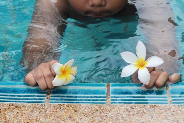 Plumeria květina v ruce chlapec u bazénu — Stock fotografie