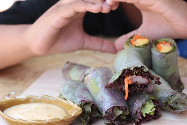 Vegetable salad wrapped into spring rolls with heart-shaped hands. — Stock Photo, Image