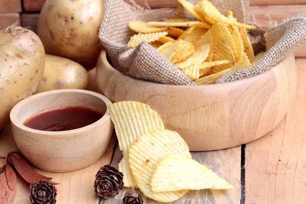 Potato chip and fresh potatoes on wood background — Stock Photo, Image