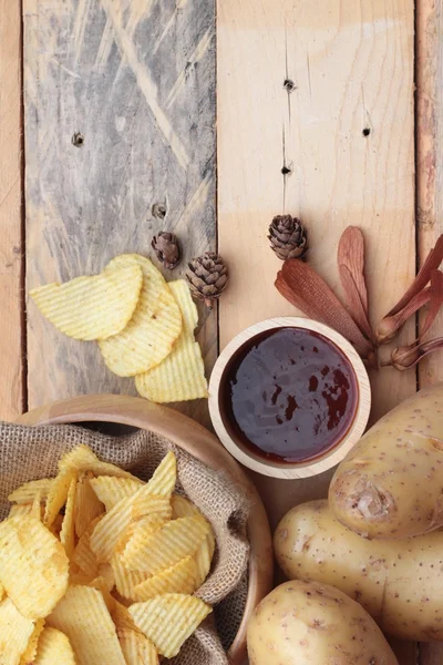 Potato chip and fresh potatoes on wood background — Stock Photo, Image