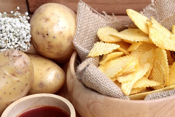 Batata frita e batatas frescas sobre fundo de madeira — Fotografia de Stock