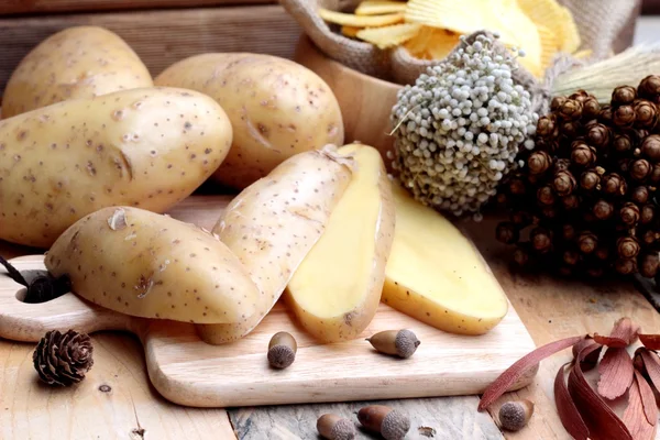 Chipsach i świeże ziemniaki na tle drewna — Zdjęcie stockowe