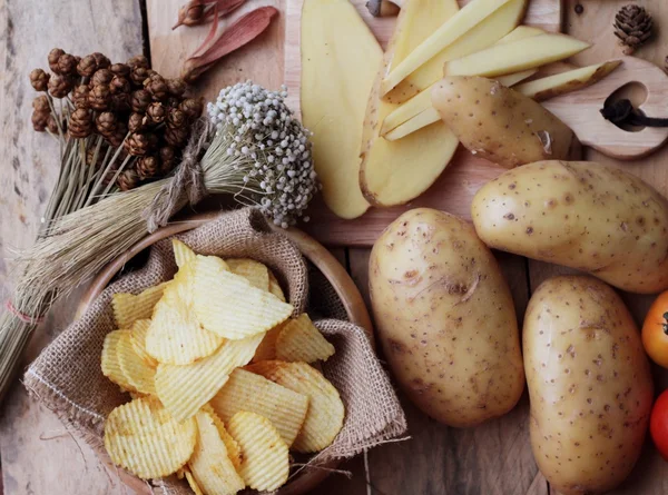 Potato chip and fresh potatoes on wood background — Stock Photo, Image