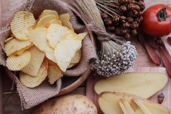 Potato chip and fresh potatoes on wood background — Stock Photo, Image