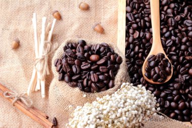 Çuval kahverengi zemin üzerine kavrulmuş kahve çekirdekleri.