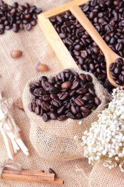 Çuval kahverengi zemin üzerine kavrulmuş kahve çekirdekleri.