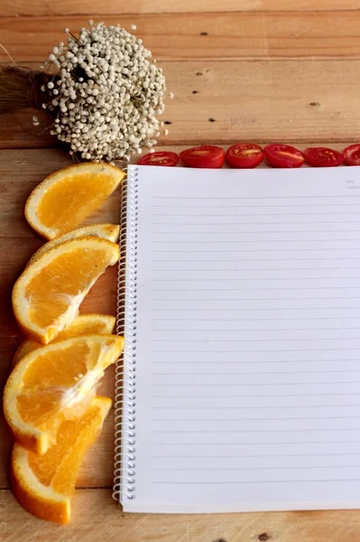 Libro diario con naranja y rodaja de tomate sobre fondo de madera . —  Fotos de Stock