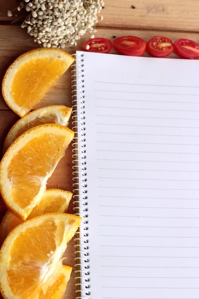 Libro diario con naranja y rodaja de tomate sobre fondo de madera . —  Fotos de Stock