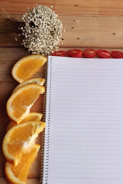 Libro diario con naranja y rodaja de tomate sobre fondo de madera . —  Fotos de Stock