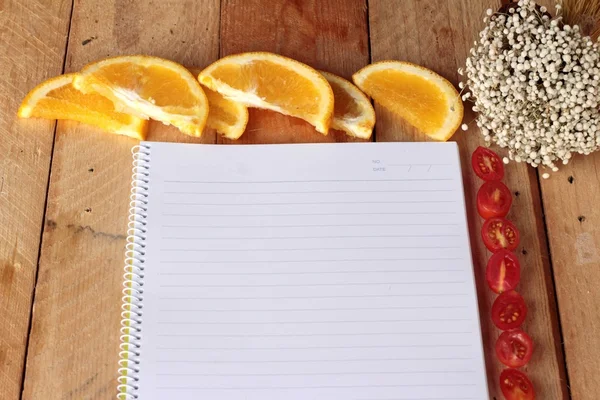 Diary book with orange and tomatoes slice on wooden background. — Stock Photo, Image