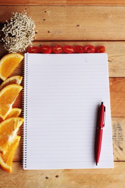 Ahşap zemin üzerine portakal ve domates dilim ile günlüğü kitap.