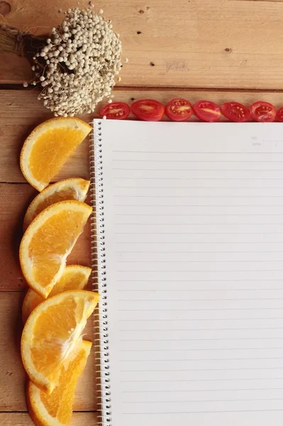 Libro diario con naranja y rodaja de tomate sobre fondo de madera . —  Fotos de Stock