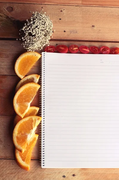 Libro diario con naranja y rodaja de tomate sobre fondo de madera . —  Fotos de Stock