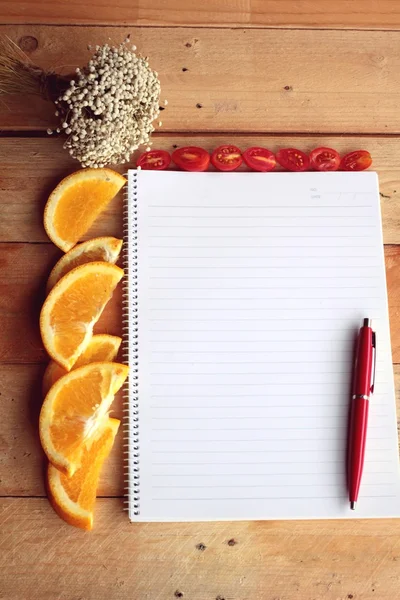 Libro diario con naranja y rodaja de tomate sobre fondo de madera . —  Fotos de Stock